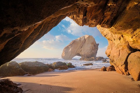 At Praia da Santa Cruz, Penedo do Guincho stands majestically as waves crash into the sandy beach