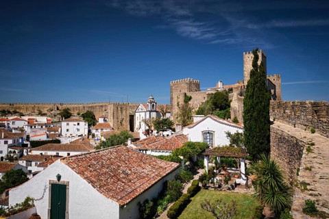 Stunning Obidos castle overlooking traditional Portuguese houses and rooftops under a clear blue
