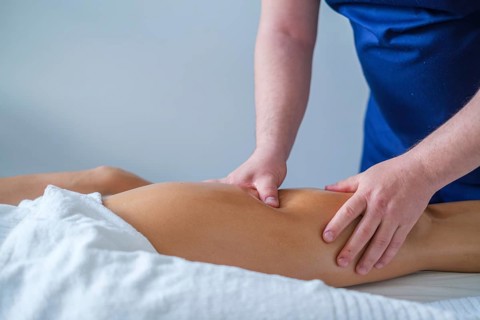 A therapist performs a soothing leg and thigh massage with oil in a spa salon. The focus is on