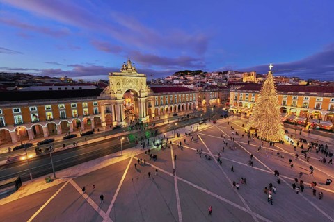 Praca do Comercio in Lisbon features a large Christmas tree and festive lights during evening