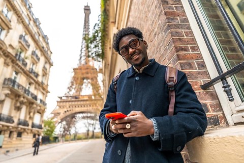 African man enjoying his travel experience in paris, standing on the street with the eiffel tower
