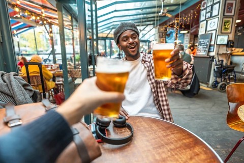 Friends enjoying a celebratory moment, raising refreshing beer glasses for a toast at a vibrant