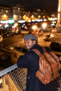 Young african man with a backpack and a cap. Smiling and looking at the camera. Standing on a