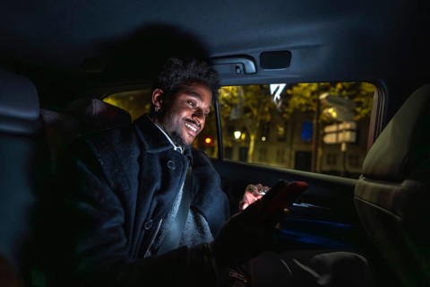 Young black man smiling and connecting with his smartphone, texting or browsing social media