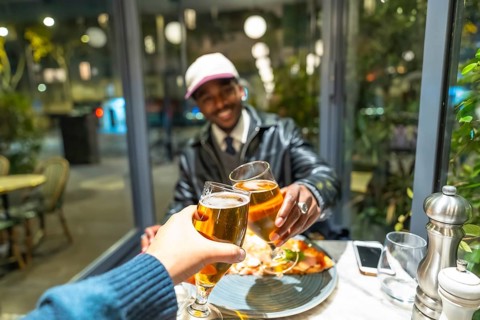 Diverse friends celebrating a successful night out, clinking beer glasses in a cheers gesture,