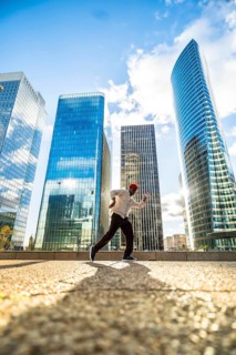 Man running with energy and freedom against a backdrop of modern glass skyscrapers, symbolizing