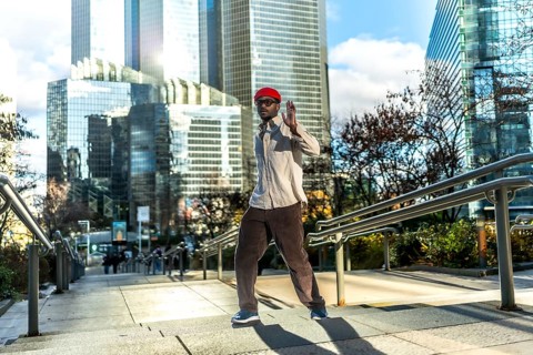 Man with red hat and sunglasses walking down an outdoor staircase in a modern central business