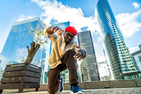 Young black man performing a dynamic street dance pose, capturing urban culture and a cool