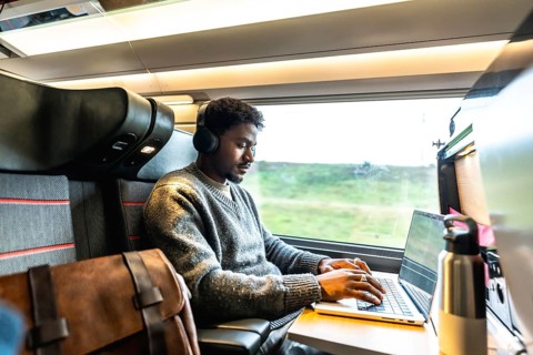 Young man wearing headphones concentrating on his laptop, working remotely or during a business