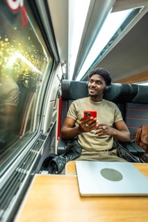 Young man wearing headphones and holding a smartphone, relaxing and enjoying the journey while