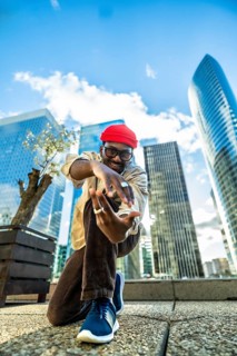 Young black man with a red beanie and glasses smiling at the camera, posing and expressing himself