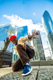Young black man in a red beret and glasses posing confidently with hands gesturing, expressing