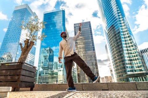 Happy black man celebrating joy and freedom with a dynamic dance on a urban plaza, surrounded by
