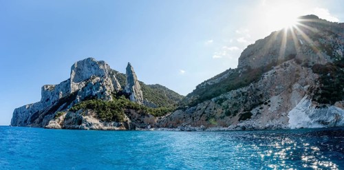 Light blue clear sea on a dream beach on Cala GoloritzÃ©, picturesque rocky coast with sun stars,