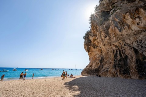 Sandy beach beach and steep cliffs with caves at Cala Luna, Sun Star, Golfo di Orosei, Baunei,