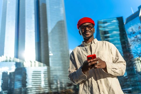 Young man smiling and checking content on his smartphone, linking to technology and modern