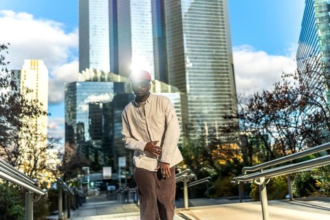 Young man wearing casual street style clothes and sunglasses, looking at camera while posing on