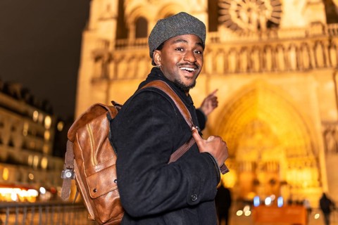 Young african american man smiling and pointing, enjoying a night out in paris and exploring an