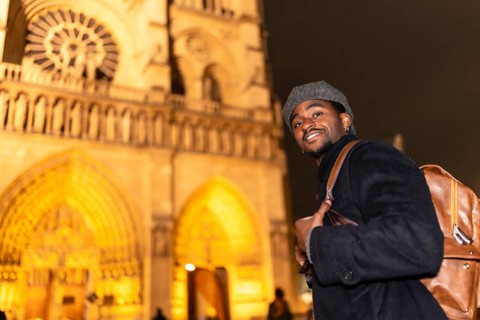 Young man smiling and wearing a backpack, exploring the historic architecture of notre dame