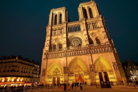 Notre dame de paris cathedral standing illuminated against the dark night sky, showcasing its