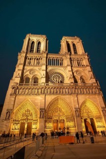 Notre dame de paris, a historic gothic cathedral, standing illuminated at night, showing its iconic