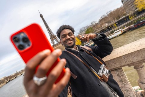 Young black man smiling and taking a selfie with a smartphone, capturing a memorable travel moment
