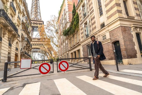 Young man crossing a street in paris, walking towards the iconic eiffel tower, embodying city