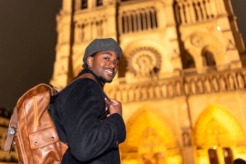 Young black man smiling, discovering french culture and history, standing in front of the