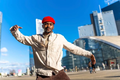 Young black man showing movement and expressing himself through dance in an urban setting with