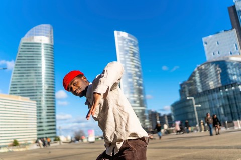 Young black man performing dynamic street dance in la defense, paris, striking a confident pose