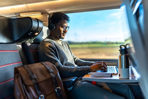 Young professional with headphones and glasses focused on laptop, working efficiently on a high