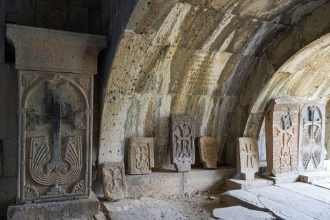 Stone room with decorated ancient grave slabs and cross reliefs under a vaulted roof, Haghpat