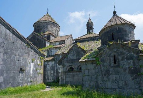 Impressive stone church towers with decorative details under blue skies and green vegetation,