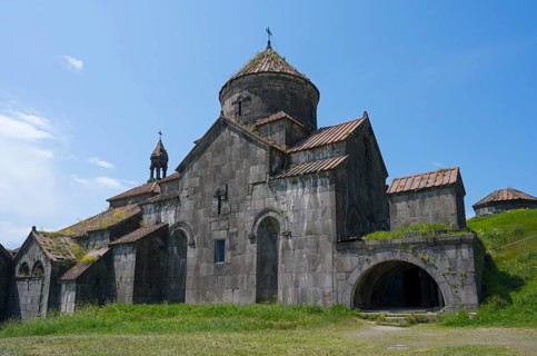 Stone monastery with several structures and domes in front of a wide meadow, Haghpat monastery,