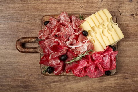 Assorted meat, appetizer, prosciutto, salami and ham, with maasdam cheese and olives, on a wooden