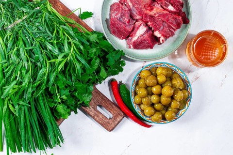 Ingredients for cooking chakapuli, canned tkemali, meat, herbs Georgian cuisine, top view