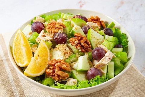 Fresh Waldorf salad, celery stalk with chicken, apple and walnuts, grapes, herbs, homemade, without
