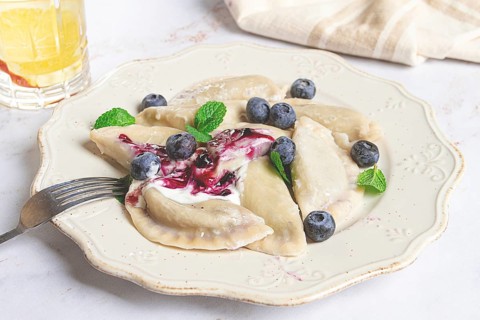 Handmade dumplings filled with sweet ingredients, arranged beautifully on a white plate, topped