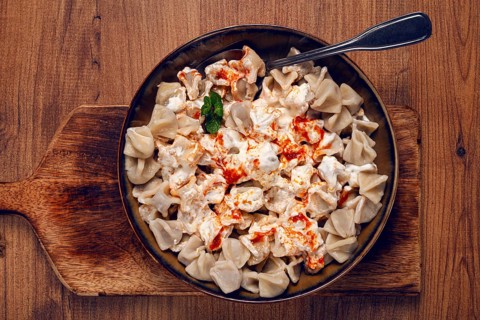 The dish features a generous serving of Turkish dumplings topped with velvety yogurt and a drizzle