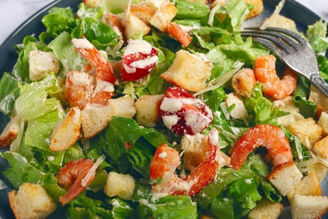 Caesar salad, with shrimp, on a marble background, top view, no people