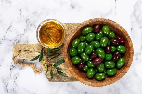 Chalkidiki olives, classic Greek green olives, in a bowl on a cutting board, top view, without