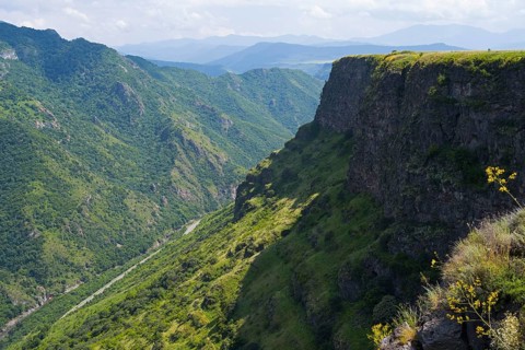 Gorge with lush vegetation and steep cliffs under blue sky in peaceful surroundings, landscape near