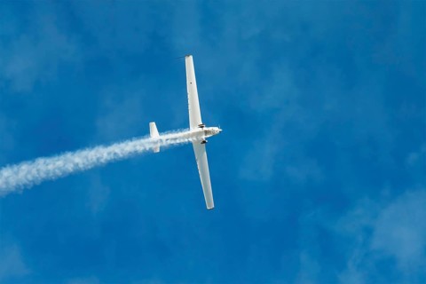 Stunt aerobatic plane performing stunts in blue sky with smoke trail. Concept of speed, difficulty,