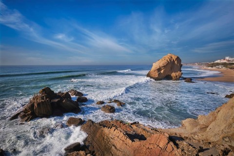 Penedo do Guincho, a large boulder rock arch at Praia da Santa Cruz, Portugal, with ocean waves and