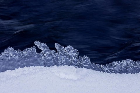 Ice formation formed by frost and freezing cold temperatures over running water of stream along