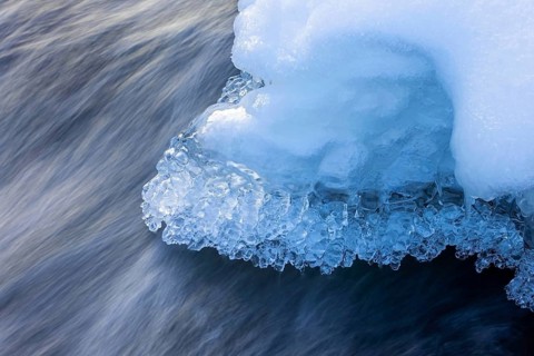 Ice formations and icicles formed by frost and freezing cold temperatures over running water of