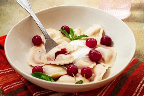 Traditional dumplings with cherries and yogurt, close-up, no people