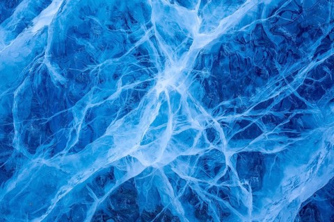 Close-up of blue ice, made of compressed snow, structure showing cracks and fissures inside