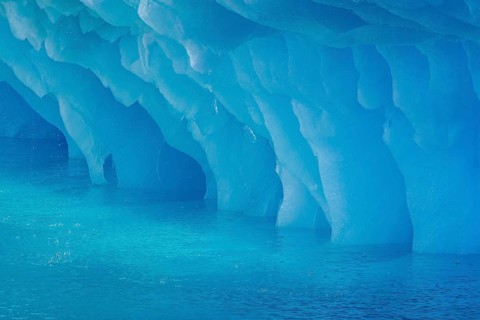 Dripping blue ice pattern from erosion by sea water on base of melting iceberg in the Arctic Ocean