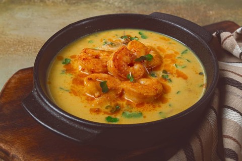 Creamy shrimp curry with spices, garnished with herbs, on a textured background, homemade, no